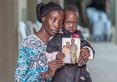 Woman and child holding photo of couple