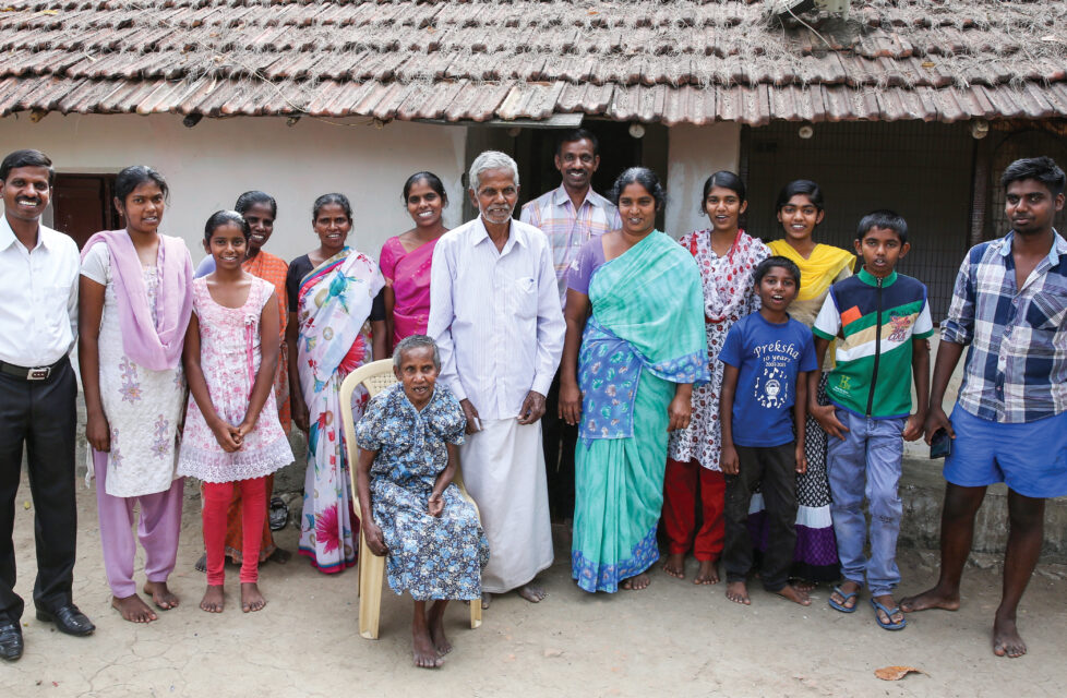 A large family stands together outside of their house